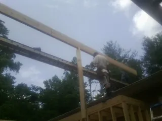 Carpenter setting a ridge beam over a new addition frame — Ice Dam Removal by Roofing Brothers in Quail Valley