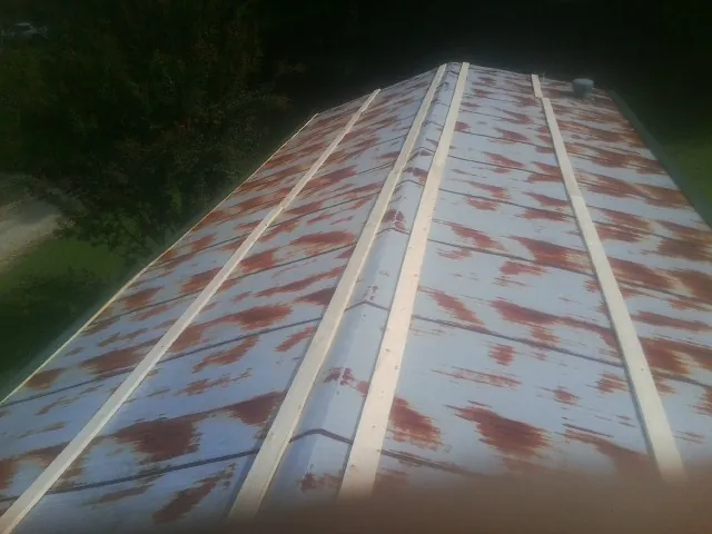 Rusted metal roof panels with new wood purlins before replacement — Storm Damage Roof Repair in Quail Valley by Roofing Brothers
