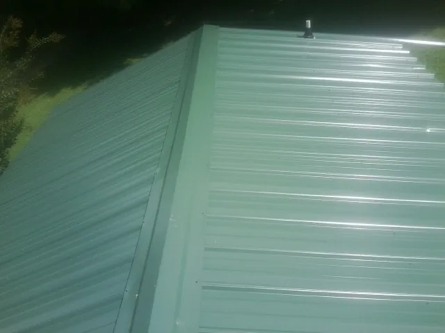 New green metal panels meeting at the ridge of a roof — Flat Roof Repair work by our crew in Quail Valley