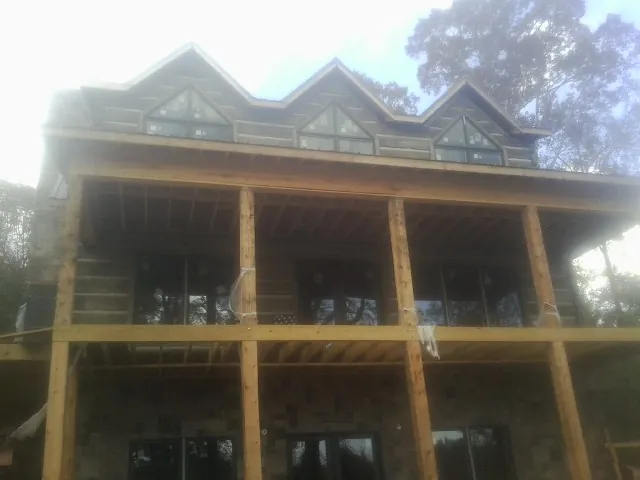 Dormers and porch framing on a large log home under construction — Roof Coating work by our crew in Quail Valley