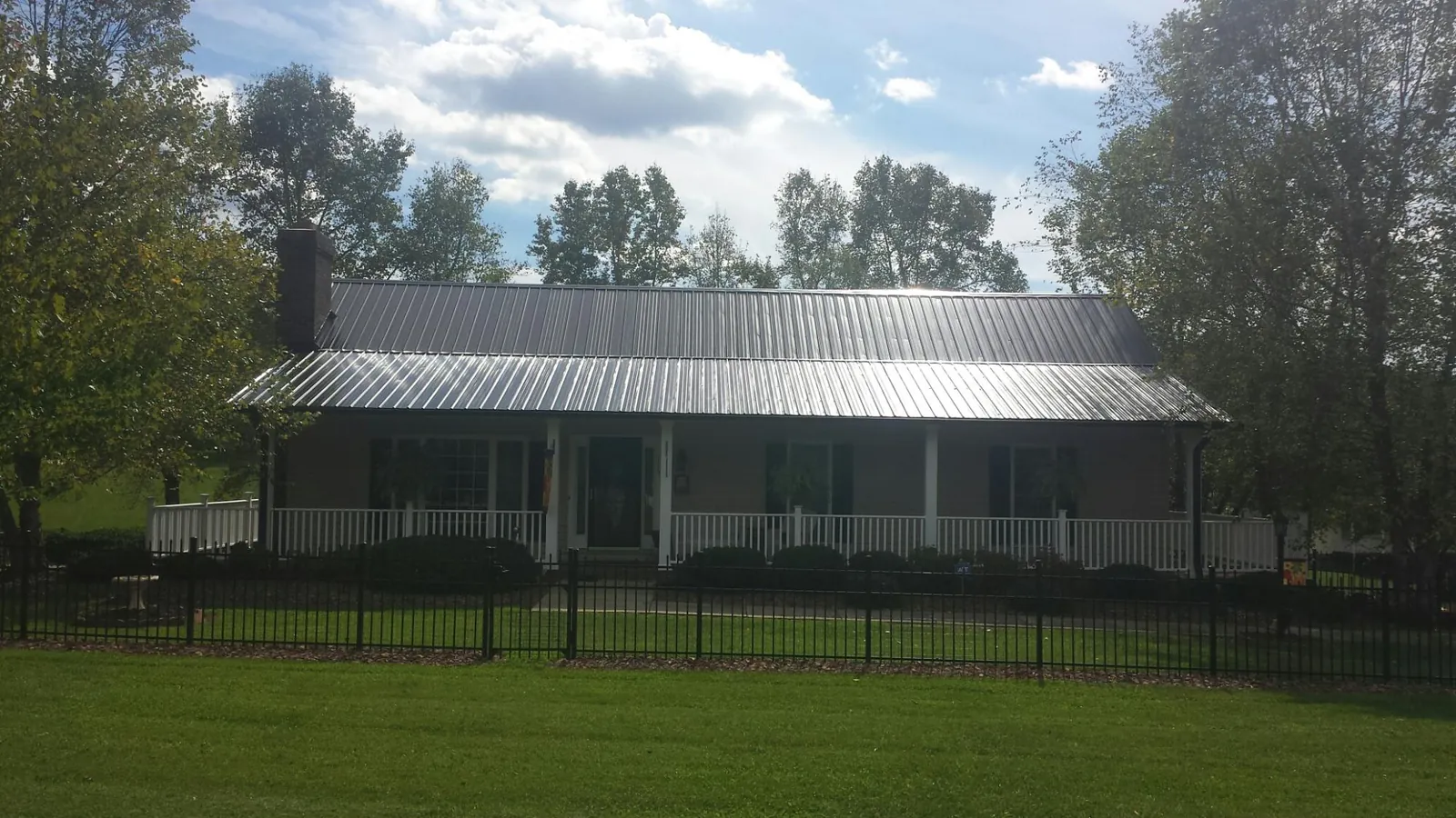 Gray metal roof on a brick ranch with a full width front porch — Gutter Guard Installation work by our crew in Quail Valley