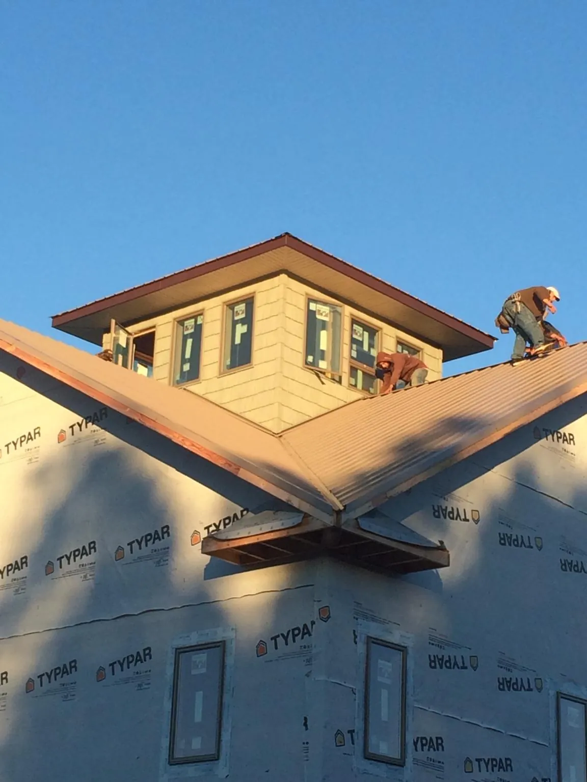 Roofers working around a rooftop cupola on a new metal roof at sunset — Roof Waterproofing in Quail Valley by Roofing Brothers